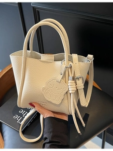 Sac à main minimaliste beige en cuir grainé avec charm chien porté main