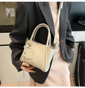 Close-up of cream leather bucket bag with puppy charm and adjustable strap