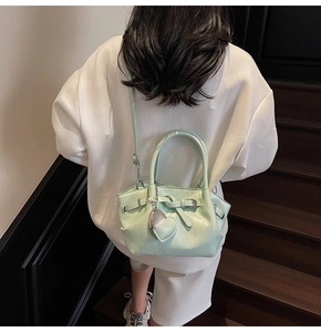 Detalle del bolso tipo cubo verde menta con colgante de corazón en escalera de madera