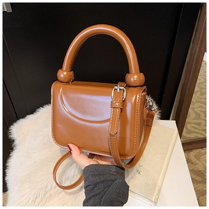 Detail of brown faux leather handbag with cylindrical handle and silver hardware