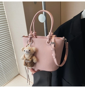 Dettaglio borsa a secchiello rosa grana litchi con un simpatico ciondolo a forma di orso