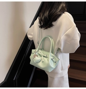 Bolso tipo cubo verde menta con colgante de corazón mostrado en un entorno elegante