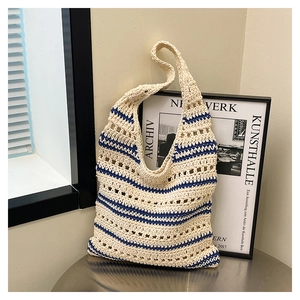 Détail d'un sac cabas en paille tissé à la main avec rayures bleu marine et ajouré