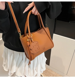 Brown lychee leather handbag with golden hardware and dog pendant on model