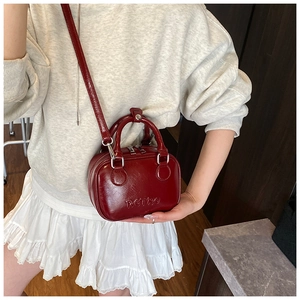 Detail view of burgundy PU leather mini Boston bag with retro embossed lettering and strap