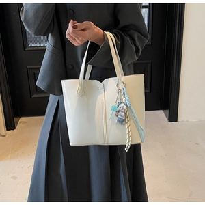 Detail of cream white tote bag featuring V-shaped opening and cute puppy charm
