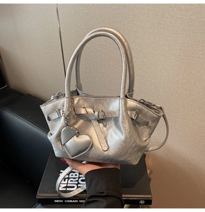 Detalle del bolso de cubo plateado con textura metálica plisada y colgante de corazón