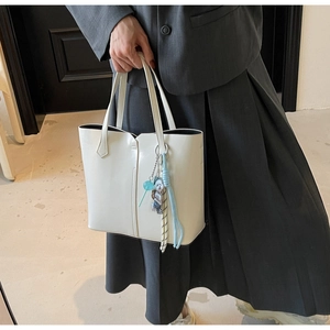 Minimalist cream tote bag with blue charm shown in a professional business setting