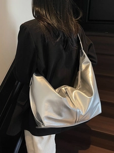 Metallic silver large tote bag with wide strap worn by model in a minimalist style