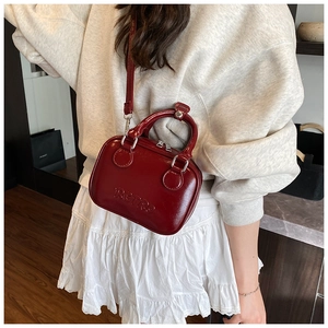 Detail showing the retro-style burgundy mini bag with glossy texture and embossed logo