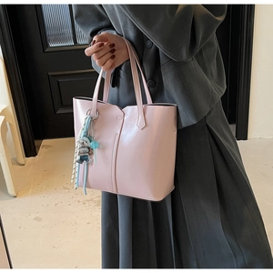 Detail of pink tote bag showing smooth faux leather texture and a cute bear bag charm
