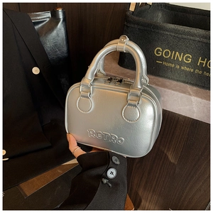 Detail of silver metallic handbag featuring embossed RETRO text and dual metal zippers