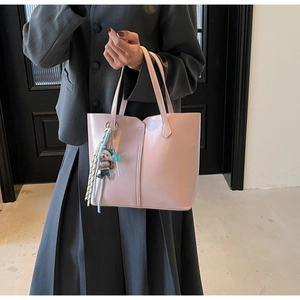 Close-up of light pink tote bag featuring a cute bear charm and woven tassel detail