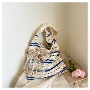 Détail du sac crocheté à rayures bleues et blanches avec nœud floral en dentelle