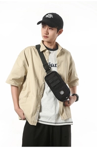Tactical black crossbody bag with MOLLE webbing worn by a model in streetwear style