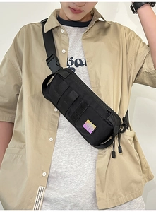 Detail of black tactical chest bag showing MOLLE webbing and reflective brand logo patch