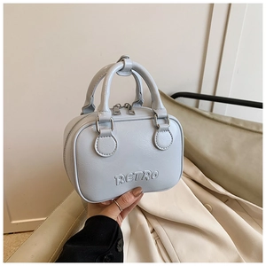 Detail of light blue mini bowling bag featuring embossed RETRO text and silver zipper