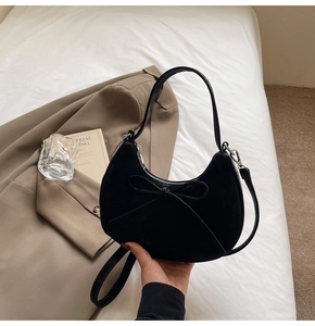 Détail du sac hobo en daim noir avec un grand nœud et une bandoulière réglable