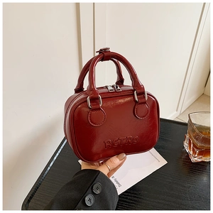 Close-up of retro burgundy glossy faux leather handbag with embossed RETRO lettering