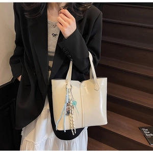 Close-up of a minimalist cream white leather tote bag worn on a shoulder for daily commute