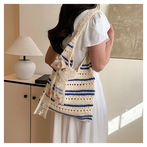 Détail arrière d'un sac cabas au crochet à rayures avec un nœud en tulle fleuri