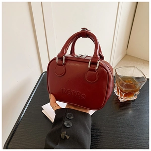 Detail of matte wine red PU leather handbag with embossed RETRO lettering and zipper