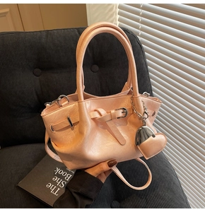 Detalle del bolso de cubo rosa perlado con colgante de corazón en fondo de terciopelo