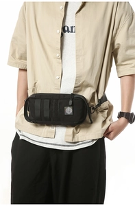 Detail of black tactical chest bag showing durable nylon texture and webbing on a model