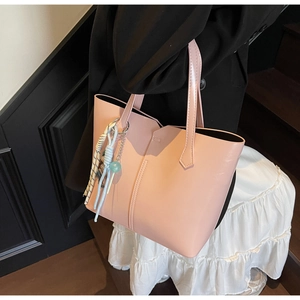 Detail of pink PU leather tote bag with decorative tassel charms and sleek handle