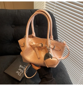 Detalle de bolso bucket rosa suave con colgante de corazón y acabados metálicos