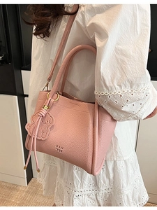 Pink lychee grain leather bucket bag with top handle, crossbody strap and dog charm