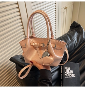Detalle del bolso de hombro rosa metalizado con colgante de corazón y correa ajustable
