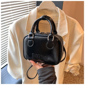 Detail of black mini bowler bag showing retro embossed logo and silver metallic zipper