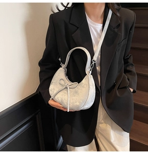 Vue détaillée du sac demi-lune argenté avec finition pailletée et nœud délicat