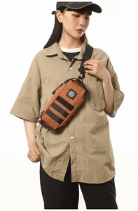 Detail of caramel brown waterproof chest bag with black tactical webbing and metal hook