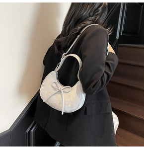 Sac demi-lune argenté avec texture métallique et nœud porté par un mannequin