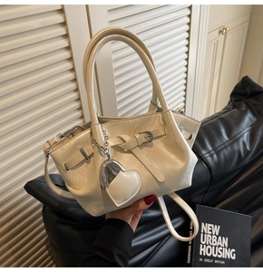Detalle del bolso de hombro blanco crema con colgante de corazón y cuero texturizado