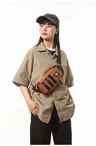 Detail of a brown waterproof nylon chest bag with adjustable strap and textured zipper