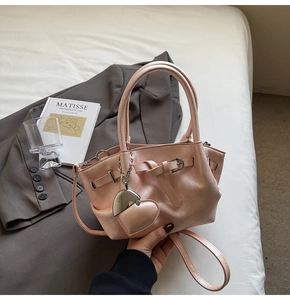 Detalle de bolso tipo cubo rosa con colgante de corazón y elegante fondo lifestyle