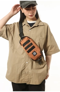 Detail view of water-resistant orange outdoor chest bag with black adjustable strap