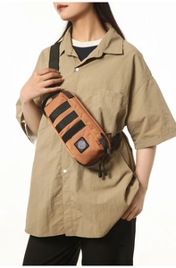 Detail of tan canvas chest bag with tactical webbing and dual drawstring zippers