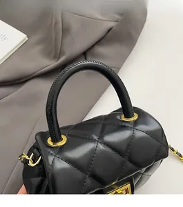 Dettaglio borsa in pelle trapuntata nera con manico elegante e catena in metallo dorato