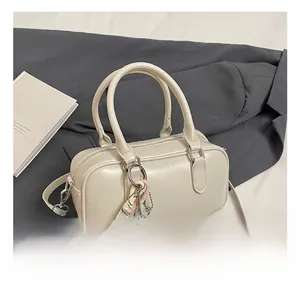 Détail du sac bowling en cuir crème avec boucles argentées et pendentif tissé