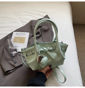 Detalle del bolso de cubo verde menta con colgante de corazón y correa ajustable