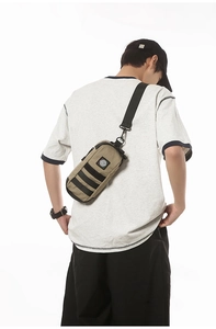 Outdoor khaki cylindrical crossbody bag with adjustable black strap shown on male model