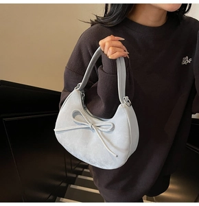 Détail du sac croissant en daim bleu clair avec nœud élégant et zip argenté