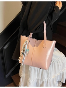 Pink glossy tote bag with beaded charm accessory shown in a casual lifestyle setting
