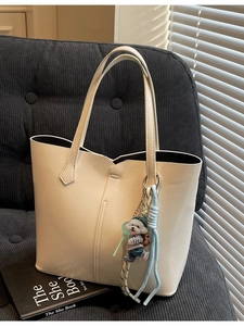 Minimalist beige tote bag with puppy charm on a sofa with soft light and shadows