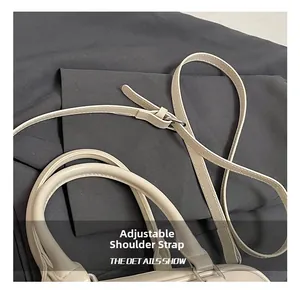 Détail de la bandoulière réglable et de l'anse arrondie du sac polochon en similicuir