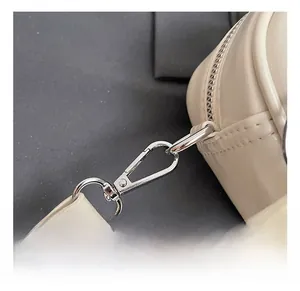 Vue macro du fermoir mousqueton argenté et des coutures sur le sac polochon beige